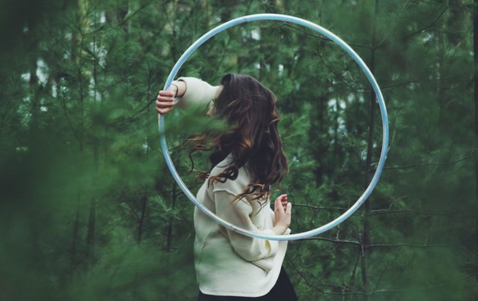 woman hula hooping in green forest